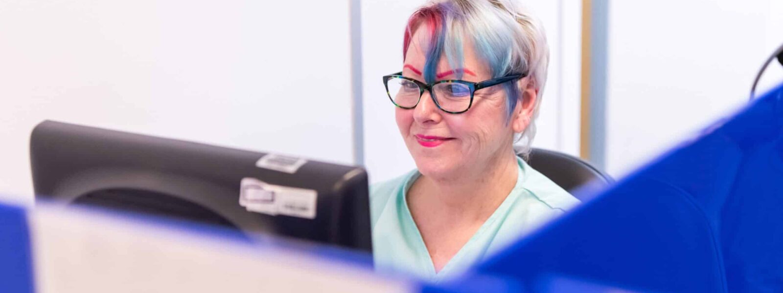 A participant sits at a computer screen smiling and completing a test at an assessment centre