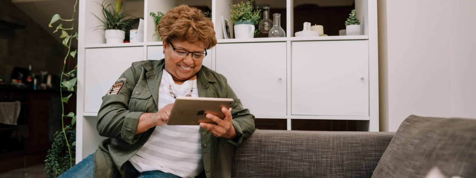 Woman sits on sofa smiling at her ipad
