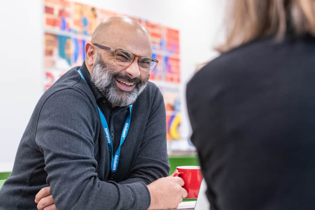 A UK Biobank staff member laughs whilst holding a mug