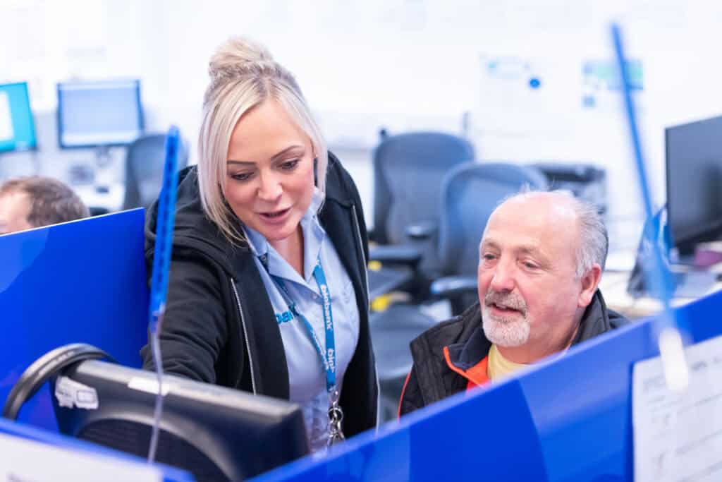A nurse helps a man on a computer