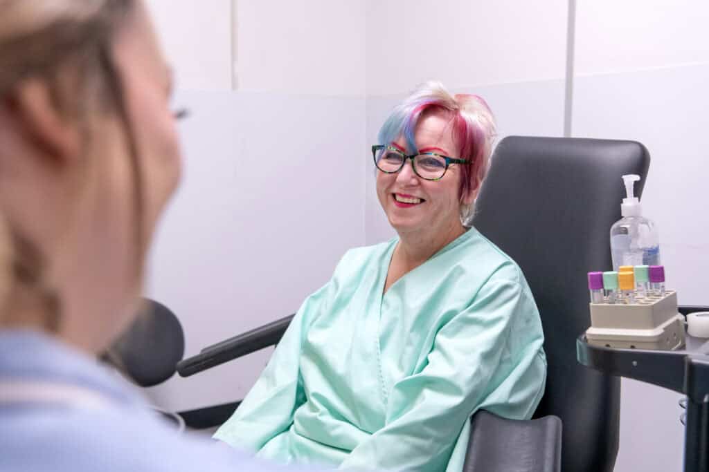 A participant smiles at a nurse, whilst sat next to sample tubes