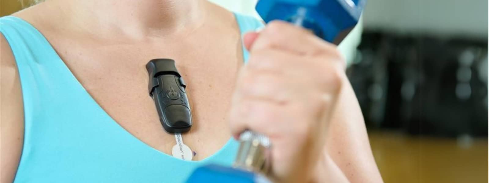 A lady uses a weight whilst wearing a heart monitor on her chest